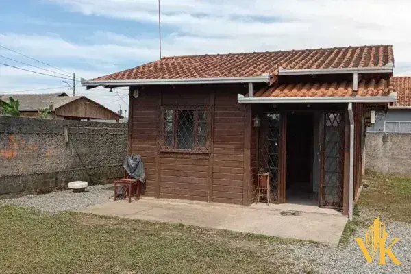Fachada frontal da casa rústica de madeira tratada, destacando a varanda coberta e o quintal amplo
